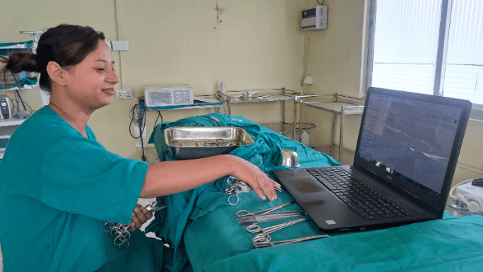 A surgical nurse managing equipment during a procedure at the Binaytara Cancer Center in Nepal