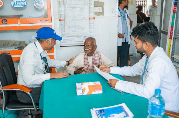 Dr. Binay Shah speaking to an elderly patient during a free cancer health camp in Nepal.