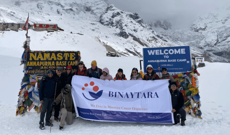 Group of trekkers at Annapurna Base Camp holding a Binaytara banner advocating for global cancer equity.