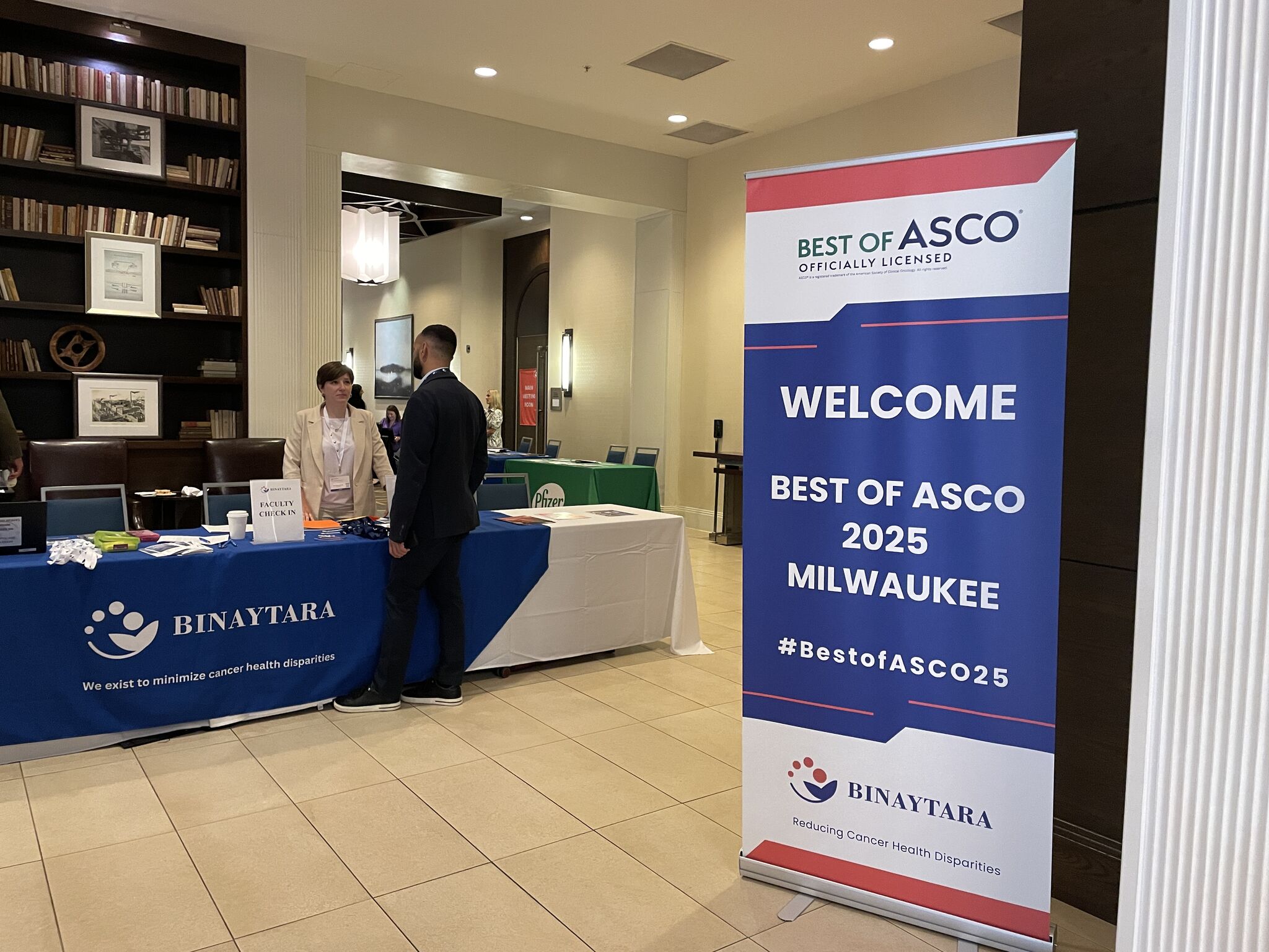 Binaytara staff welcomes attendees at Best of ASCO 2025 Milwaukee conference promoting oncology education in underserved communities.