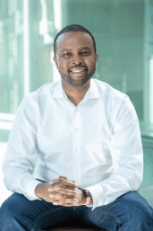 Portrait of Dr. Kingsley Ndoh, founder and CEO of Hurone AI, sitting in a bright modern space