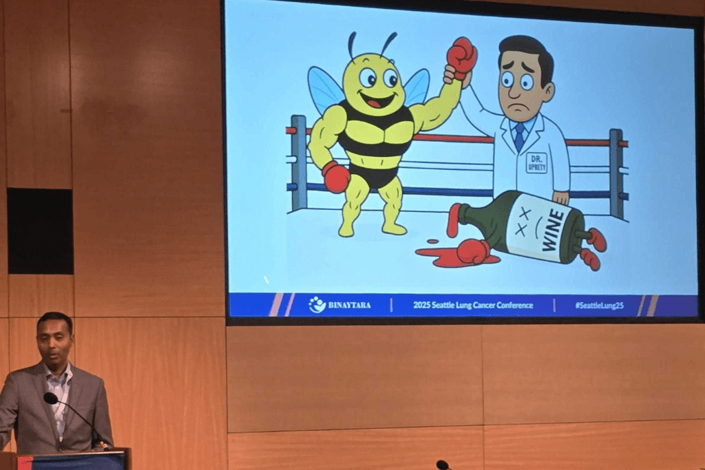Dr. Ram Subramanian standing at the podium presenting a humorous debate on Antibody-Drug Conjugates at the Seattle Lung Cancer Conference.